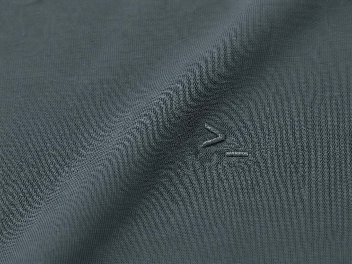 Macro detail of the small tone-on-tone embroidered symbol over the heart, left side
