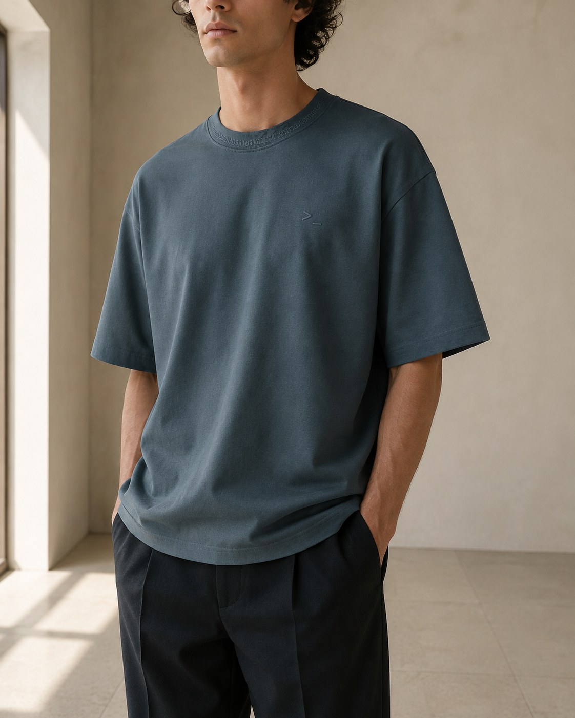 Oversized cotton silhouette: dropped-shoulder t-shirt, a thin ASCII signature around the collar and a small embroidered mark over the heart